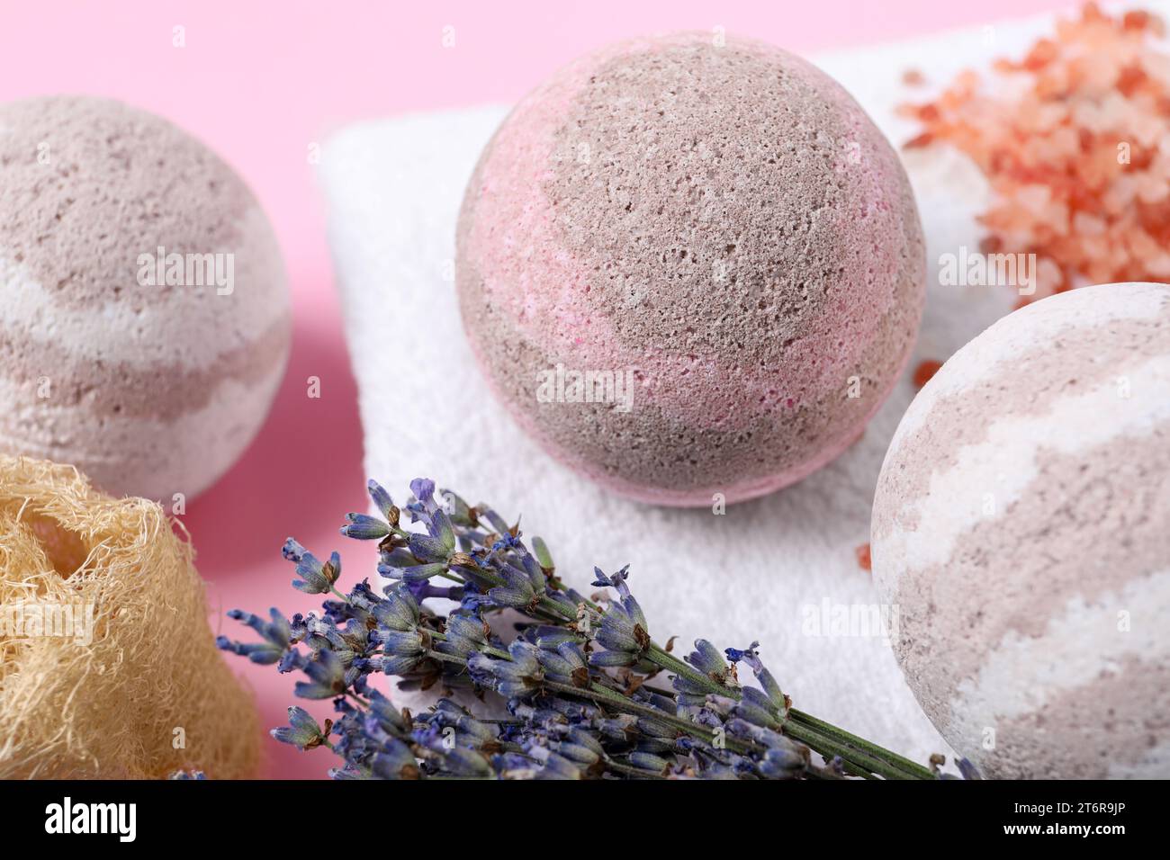 Bath bombs, towel, lavender and loofah sponge on pink background, closeup Stock Photo