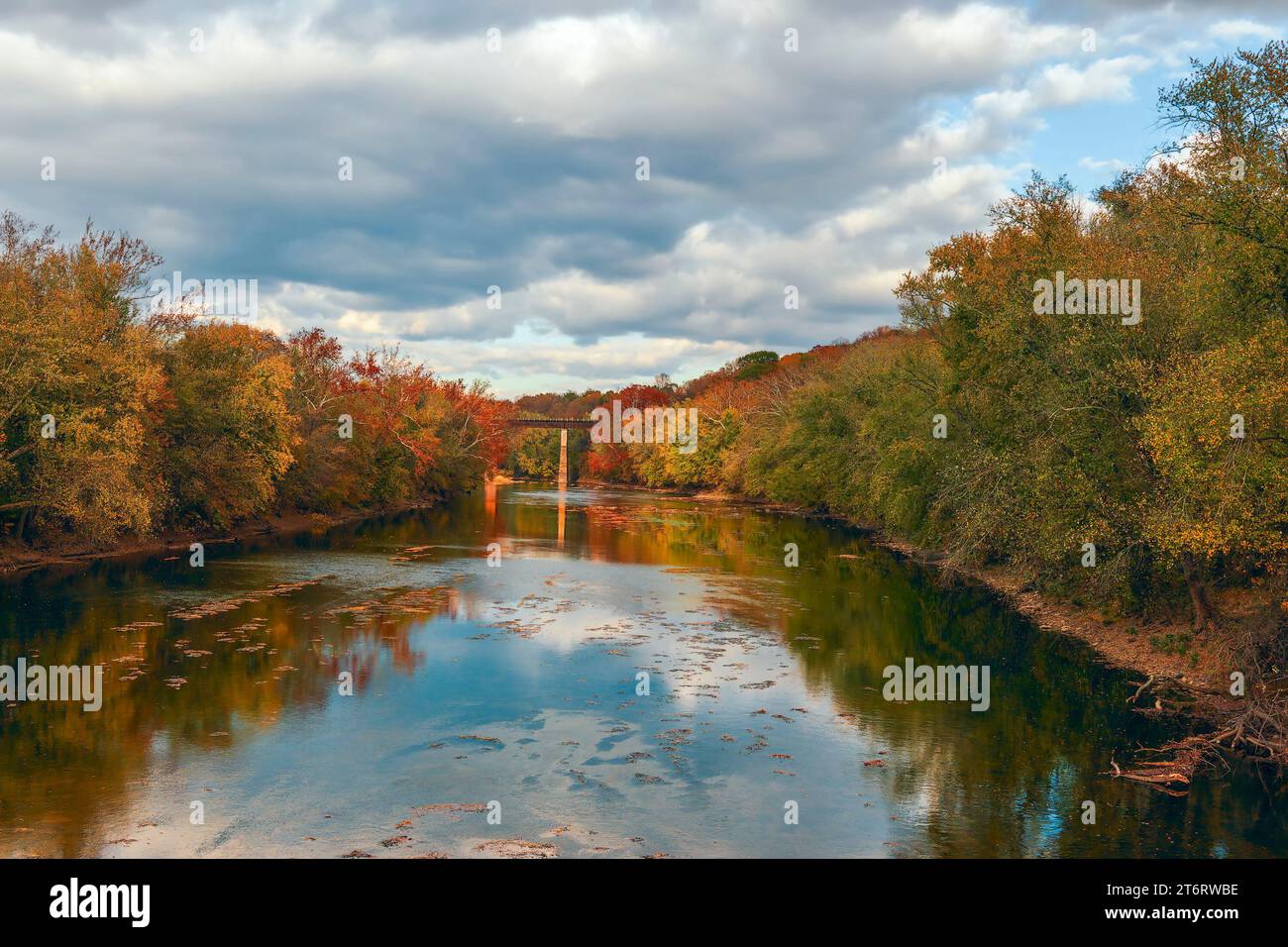 Colorful trees along the banks of the Monocacy River and a railway bridge on the background. Frederick County. Maryland. USA Stock Photo