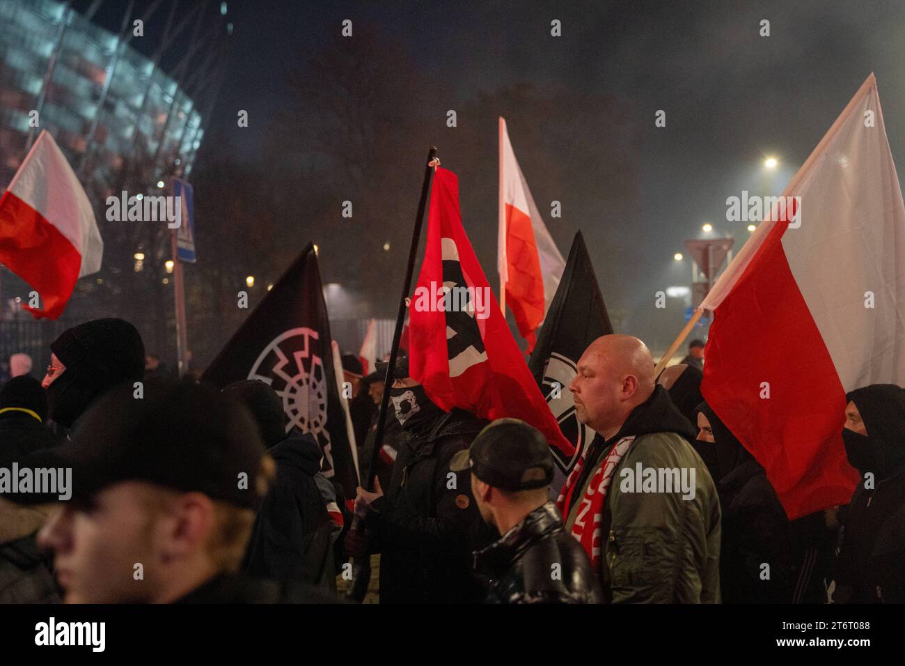 A masked man carries a red flag with a Celtic cross in a white circle during celebrations of the 105th anniversary of Poland regaining independence in Warsaw, November 11, 2023. Thousands of people gathered in the Polish capital, Warsaw, during the previously controversial annual Independence March - true - wing and nationalist Youth All-Poland and ONR groups on the occasion of Independence Day. Warsaw Poland 105th Poland s Independence Day In Warsaw Copyright: xMarekxAntonixIwanczukx MAI01389 Stock Photo