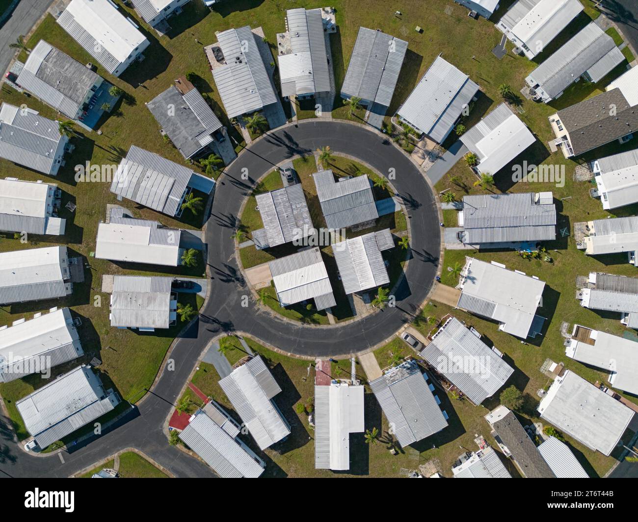 A mobile home neighborhood, configured in a circular layout, is shown from an aerial, daytime view among the community's streets. Stock Photo