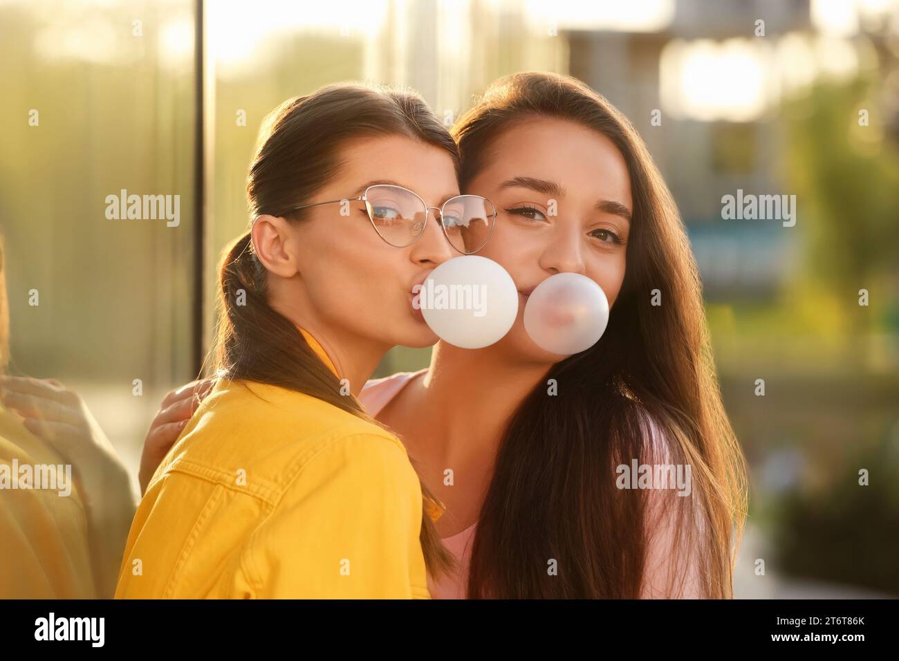 Beautiful young women blowing bubble gums outdoors Stock Photo Alamy