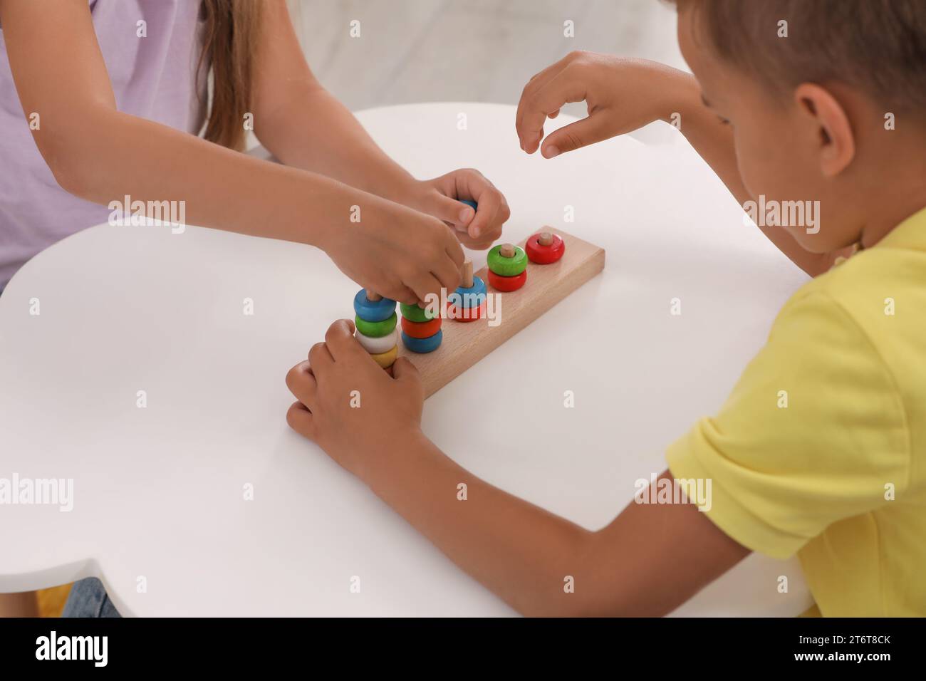 Little children playing with stacking and counting game at desk