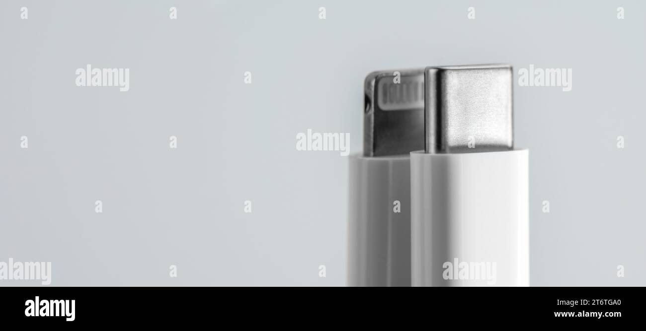 Usb c cable and lightning cable on gradient gray background. Selective focus. Stock Photo
