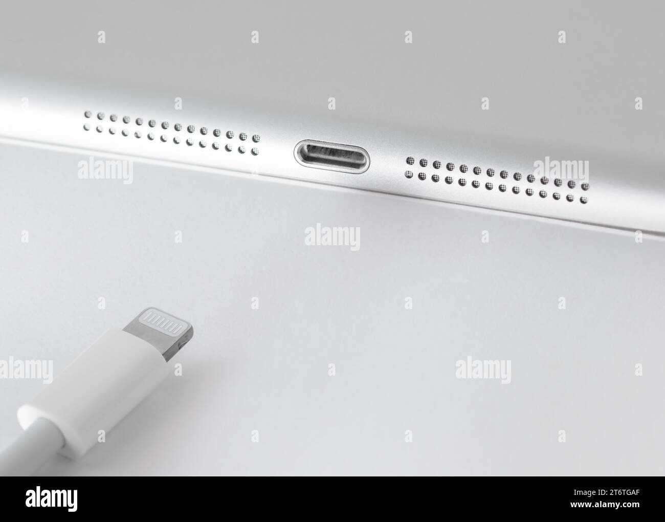 View of Apple Lightning cable and gadget on a white table with empty space, close-up. Stock Photo
