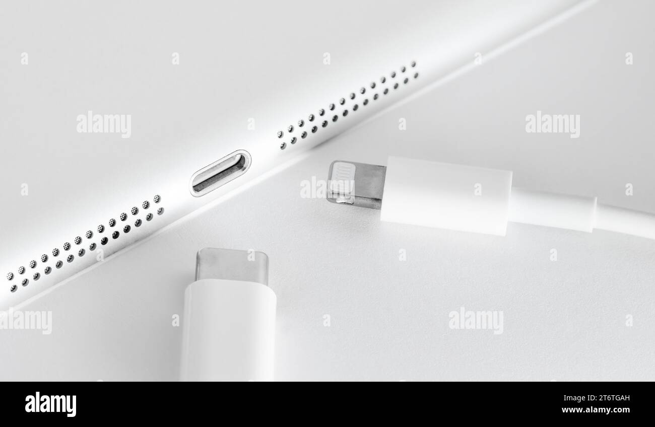 Uniform USB-C concept for all mobile phones. USB C and Lightning cables. Usb c cable and lightning cable in front of device. Selective Focus. Stock Photo