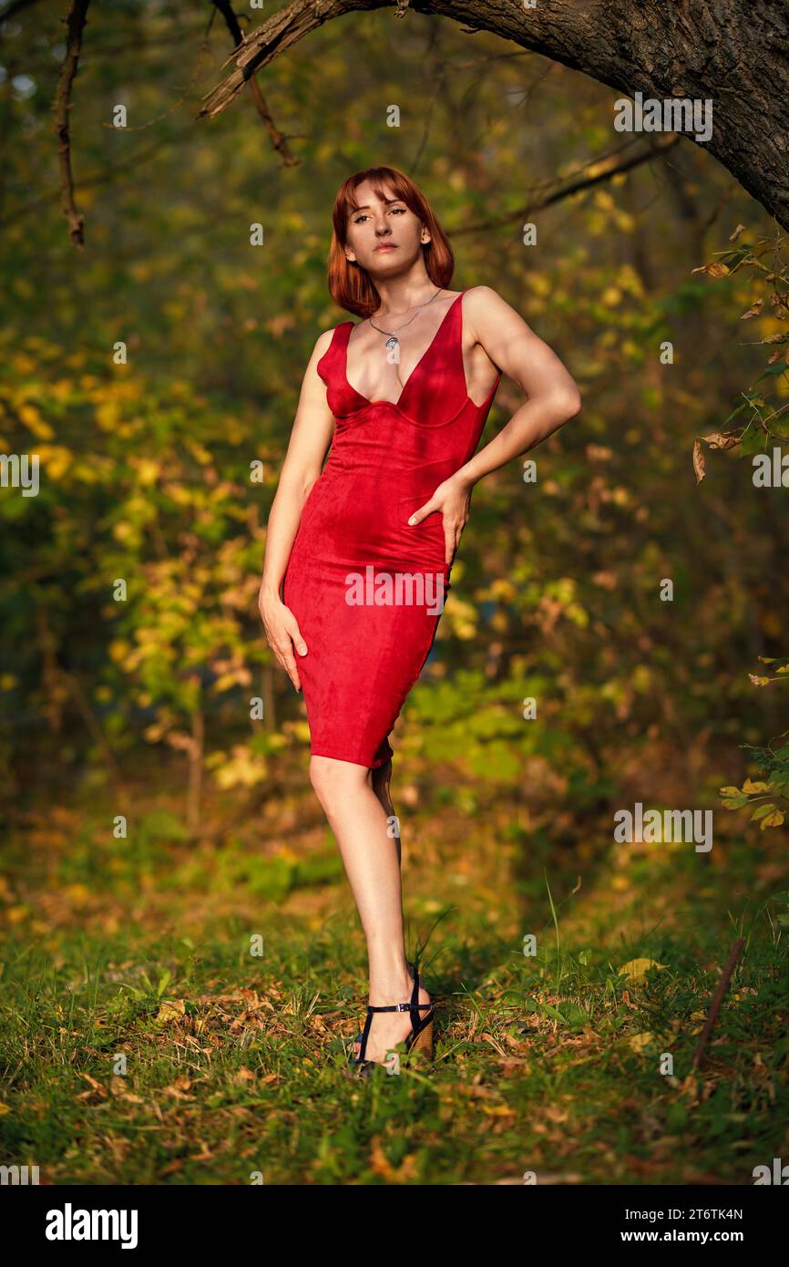 A redhead woman poses gracefully in the warm glow of an autumn sunset. Perfect for capturing the magic of fall and the beauty of the season. Stock Photo