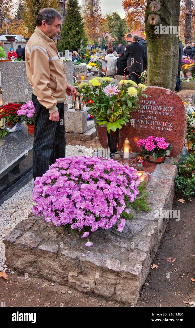 Man visiting parents and brother's grave on All Saints Day at Saint Lawrence Cemetery in Wroclaw, Lower Silesia, Poland Stock Photo