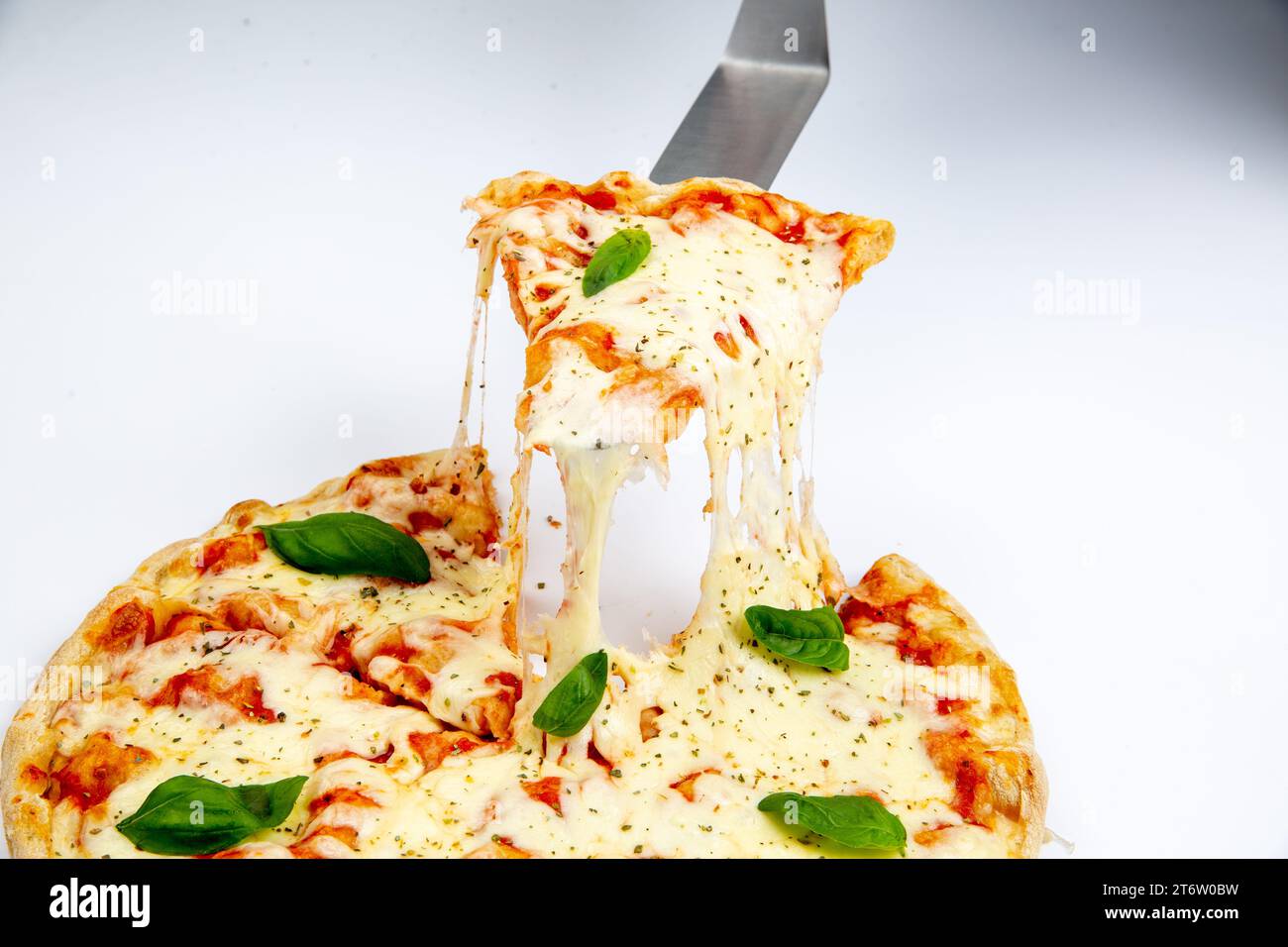 A close-up image of a large slice of pizza being held up by a fork Stock Photo