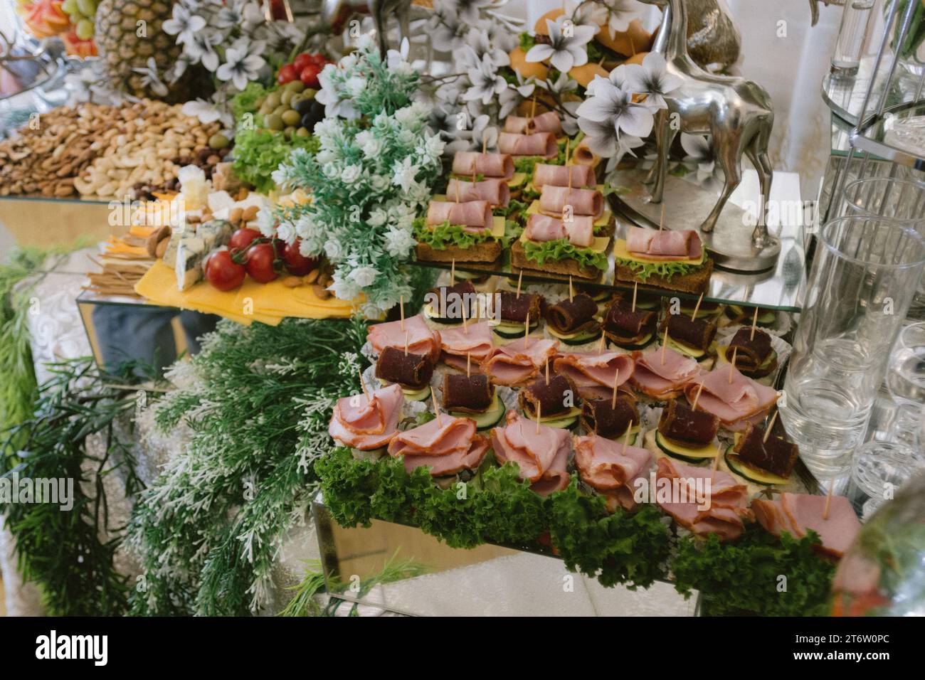 A selection of freshly prepared ham sandwiches and other cured meats is displayed on a white platter Stock Photo
