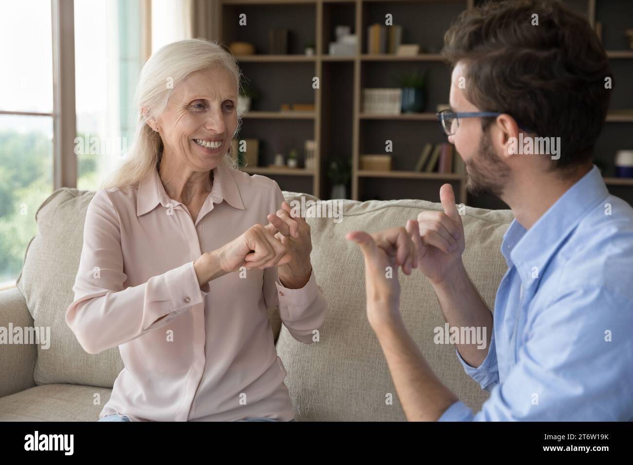 Grownup son communicates with senior mother using gestures Stock Photo