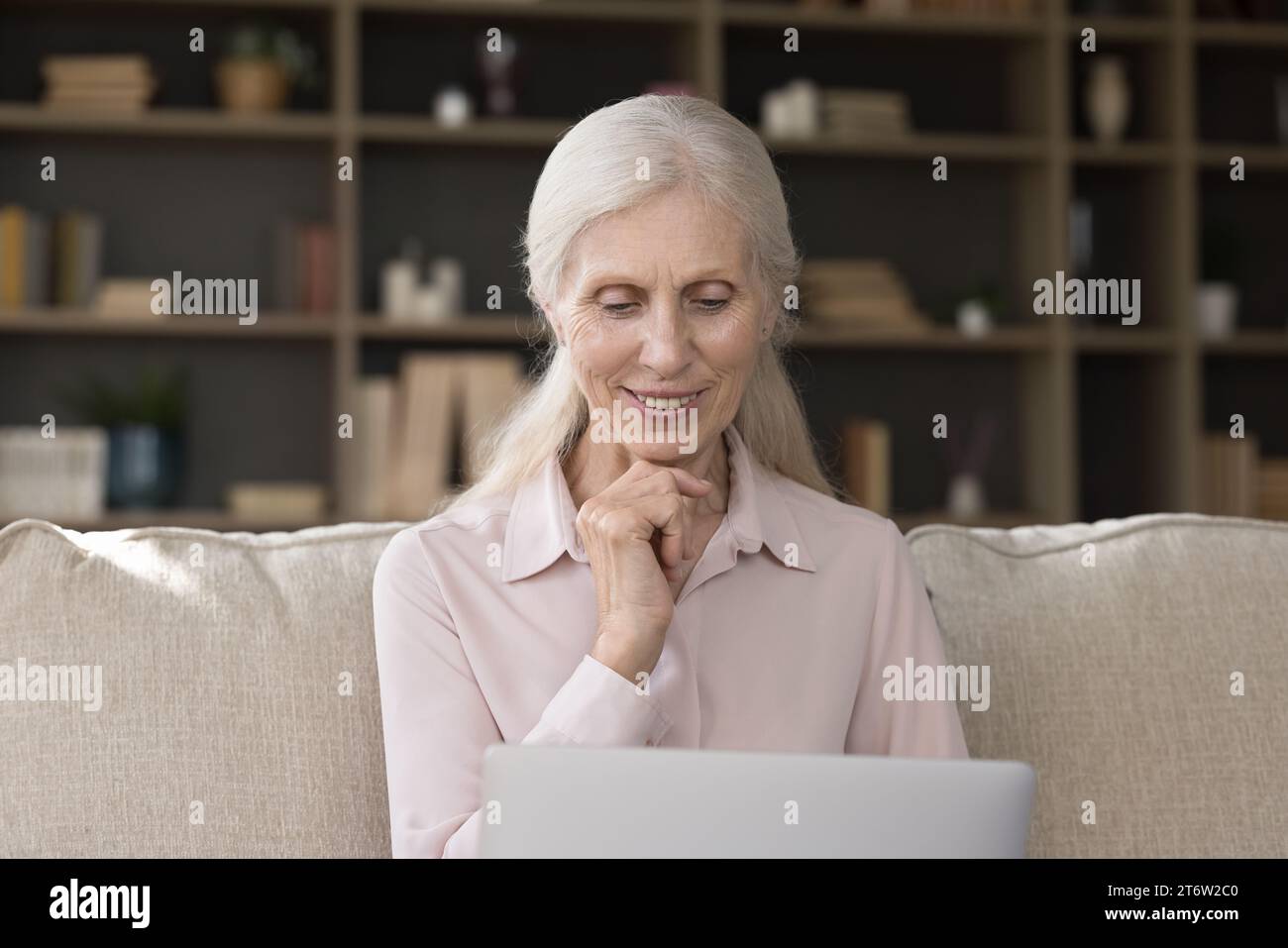 Pensive mature woman sit on sofa at home with laptop Stock Photo - Alamy