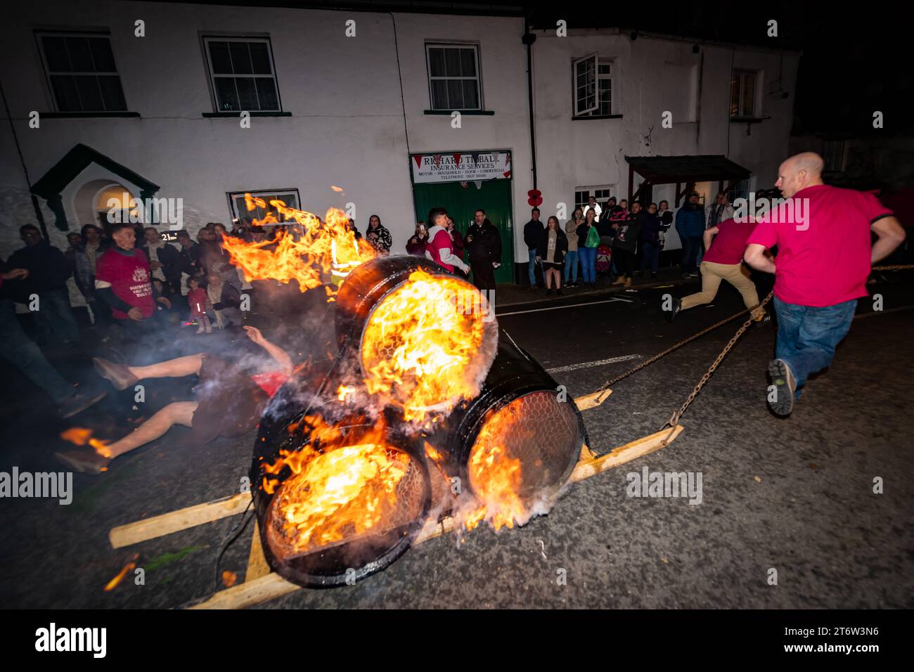 Hatherleigh, UK. 11 Novmeber 2023. High speed flaming barrel run through the town centre of Hatherleigh for the Carnival & Tar Barrels, offering raw, Pagan energy since 1903. Stock Photo