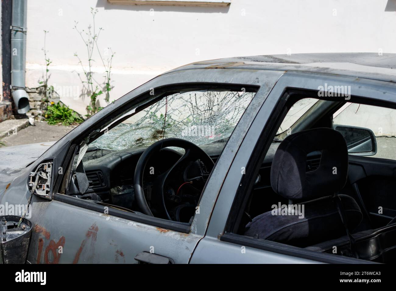 An old car with a broken windshield and traces of vandalism on the body