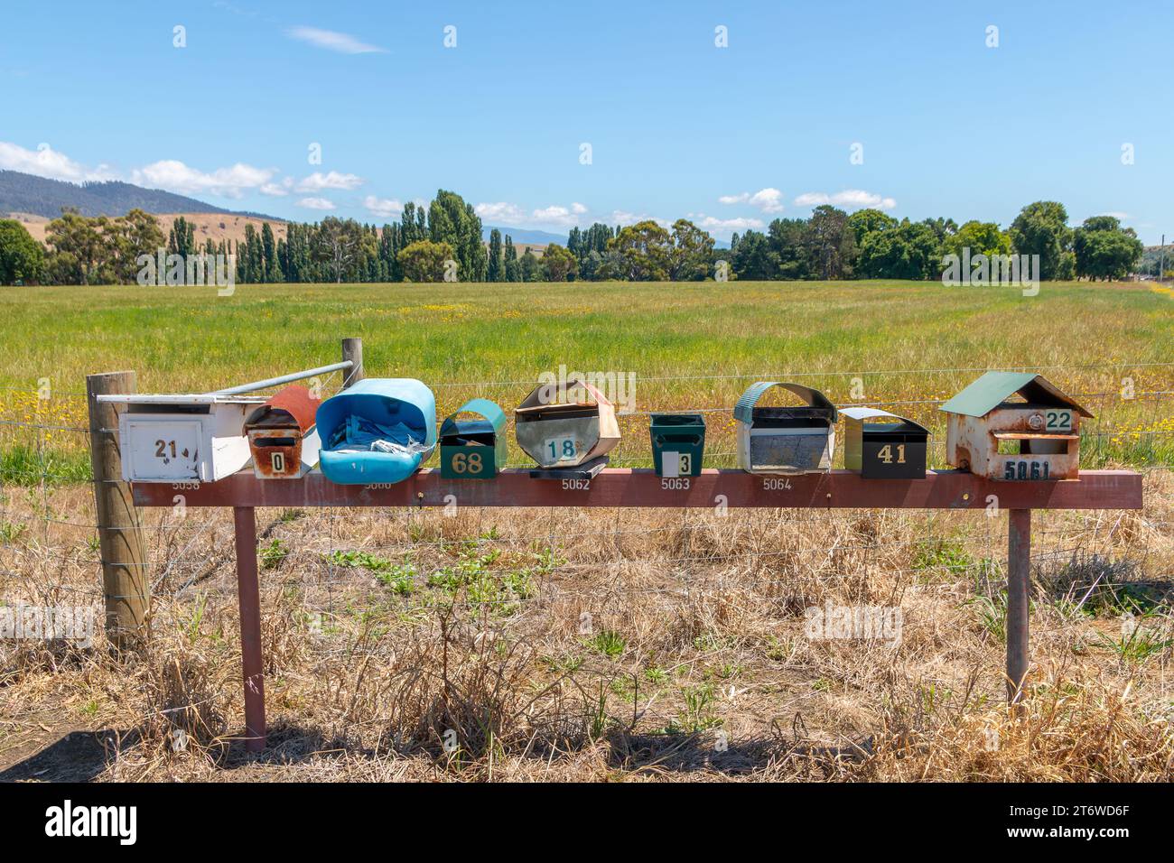 Tasmania, Australia - 26 December 2022: row of countryside letterboxes with green field, trees and blue sky background Stock Photo