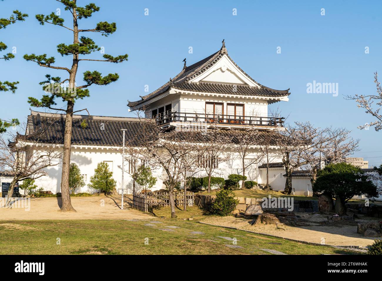 Fukuyama castle in Japan. The restored Tsukimi yagura, with its moon-viewing balcony, with cherry blossom trees and a clear blue springtime sky. Stock Photo
