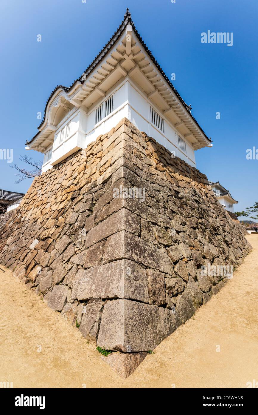 Fukuyama castle in Japan. Wide angle view, Ishigaki stone walls with corner stones and the Tsukimi yagura, moon-viewing turret against blue sky. Stock Photo