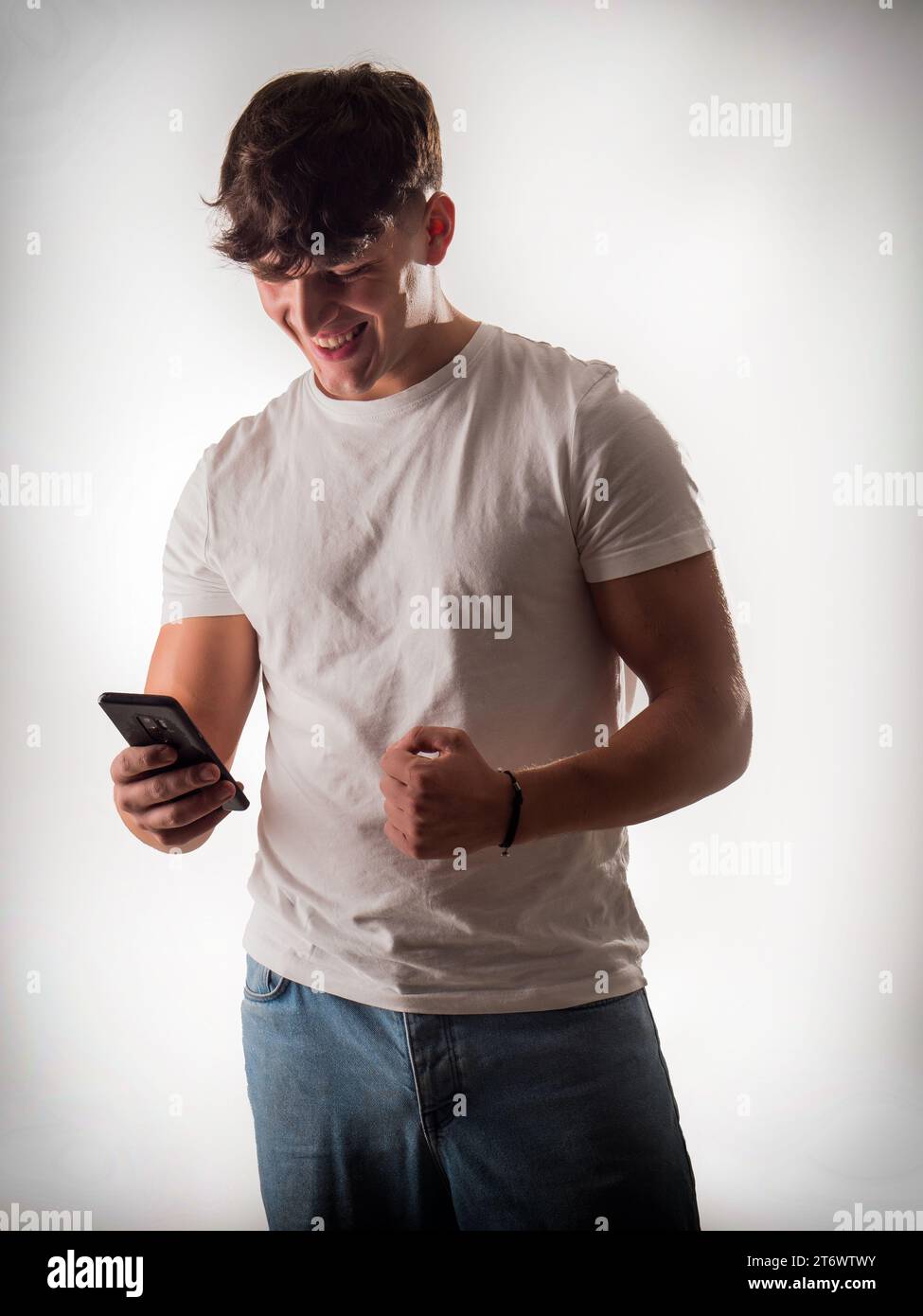 A man laughing while holding a cell phone. A Joyful Moment Captured: A Handsome Man Laughing With a Cell Phone in a Studio Setting Stock Photo
