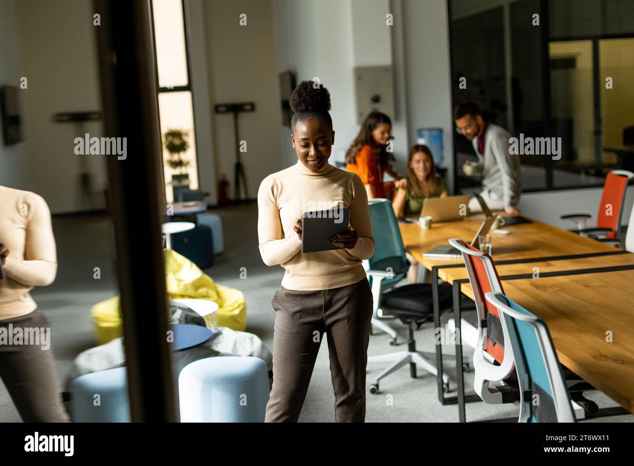 Young African American woman standing with digital tablet in front of her team at the modern office Stock Photo