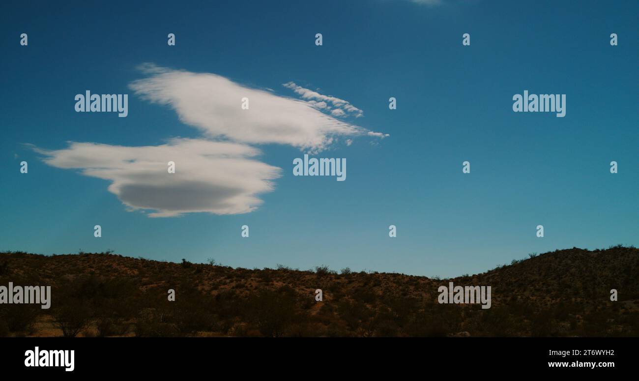 A stationary lenticular cloud (stratocumulus lenticularis) hovers above a foot hill in the Mojave desert. Stock Photo