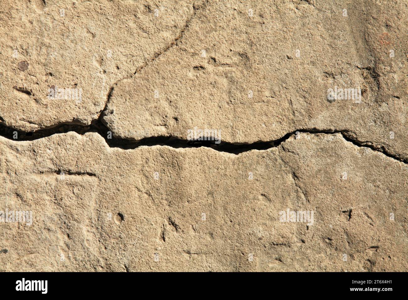 Crack in the concrete cladding of an old house. Rough, uneven surface. Cement plaster on a brick wall, texture, background. Ancient backdrop Stock Photo