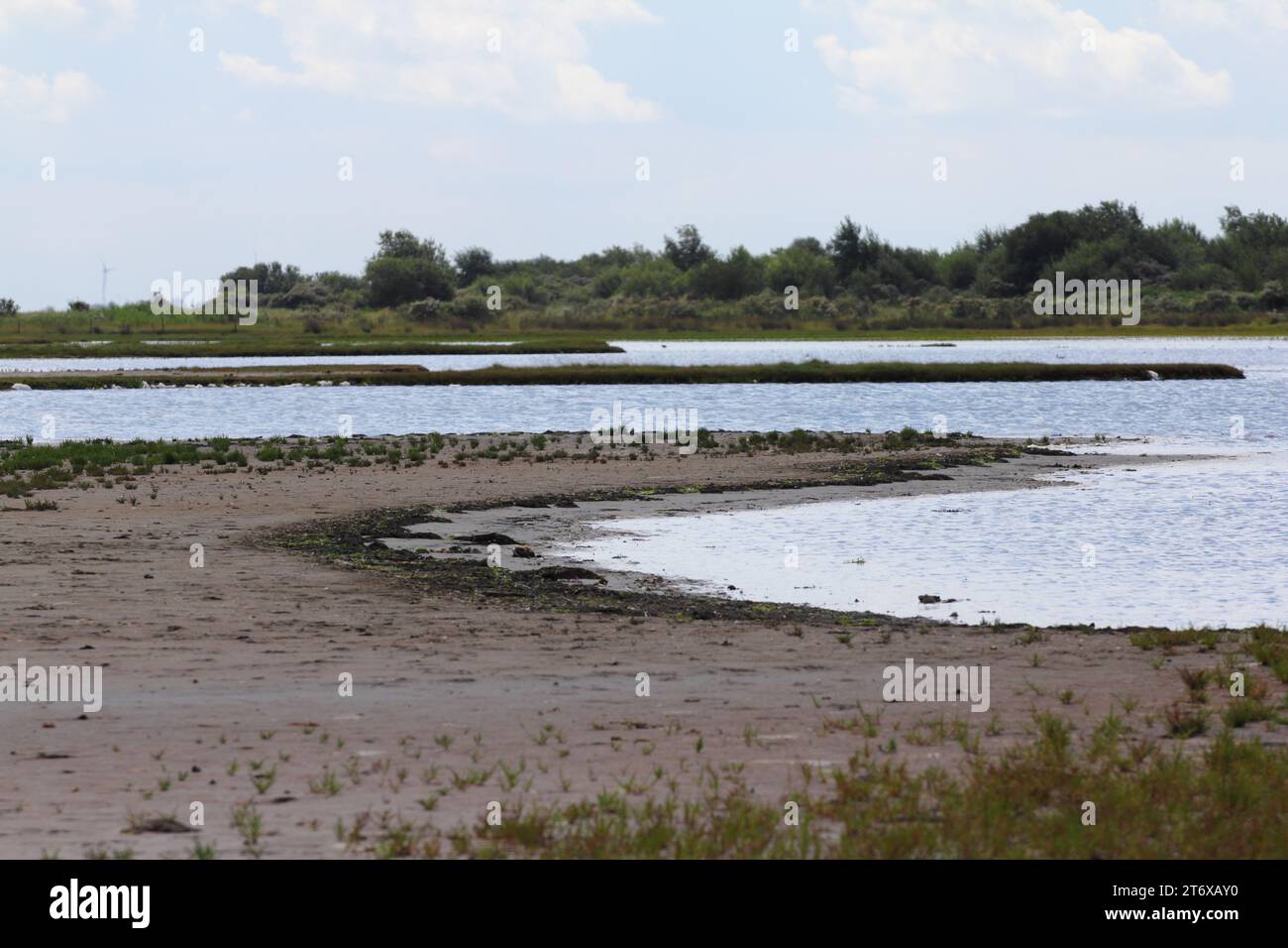 Water surface with small sand island, blue sky in background Stock Photo