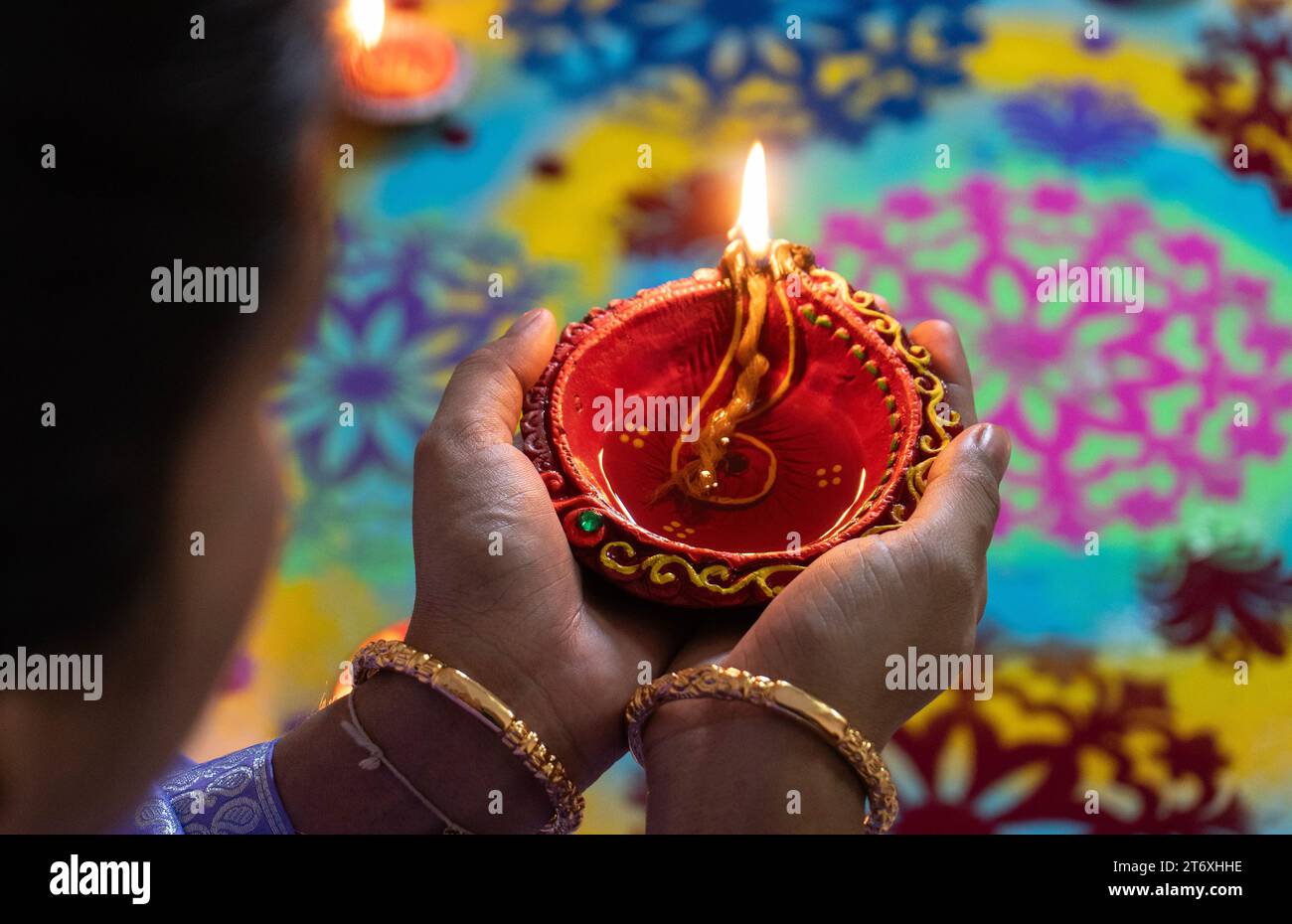 A woman holds an oil lamp wearing traditional costume on the occasion