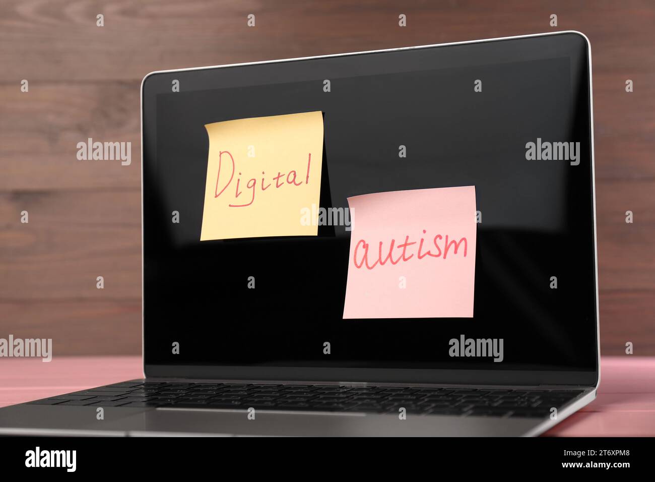 Sticky notes with phrase Digital Autism attached to laptop on table, closeup. Addictive behavior Stock Photo