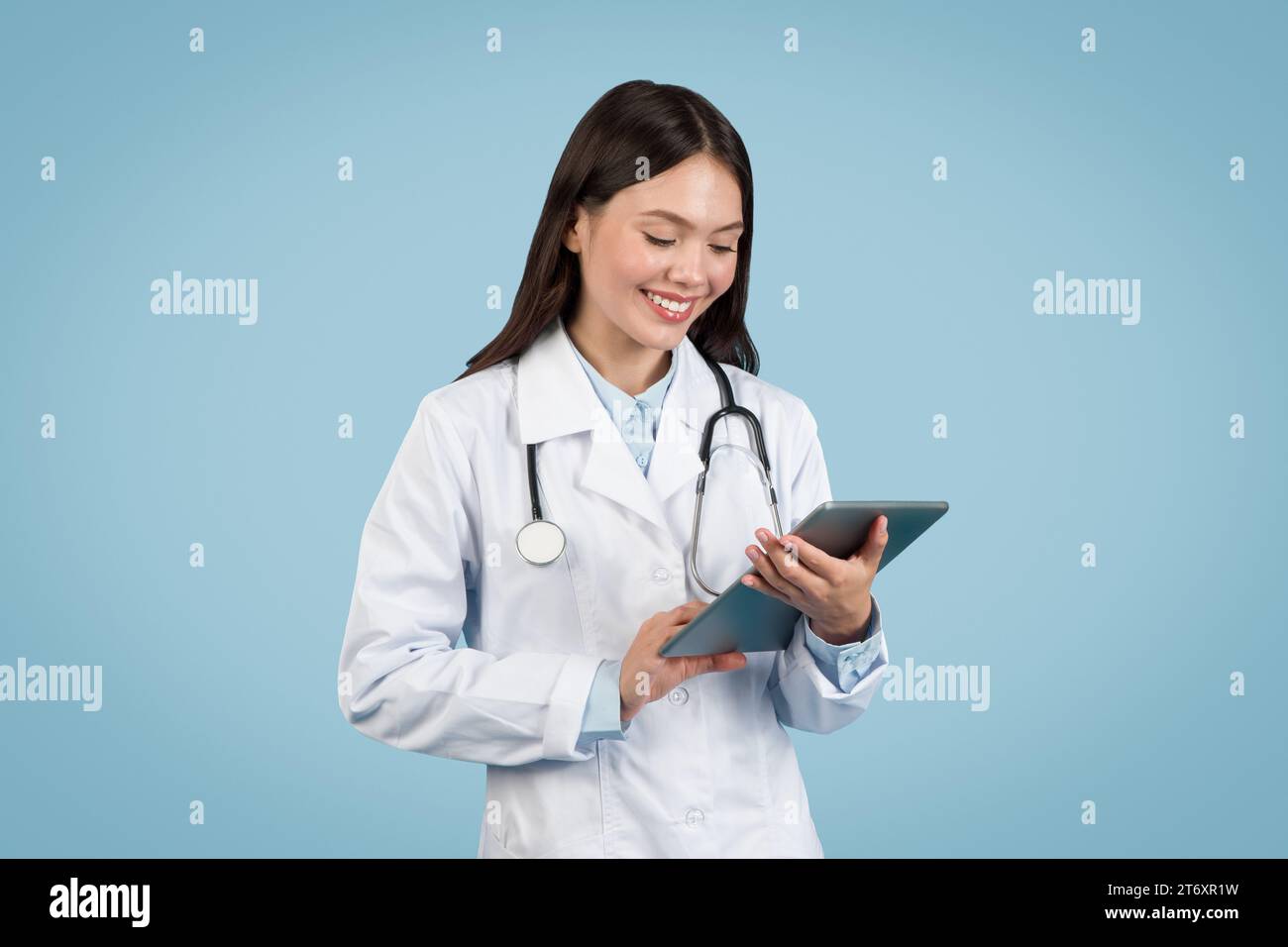 Young female doctor using digital tablet, smiling Stock Photo