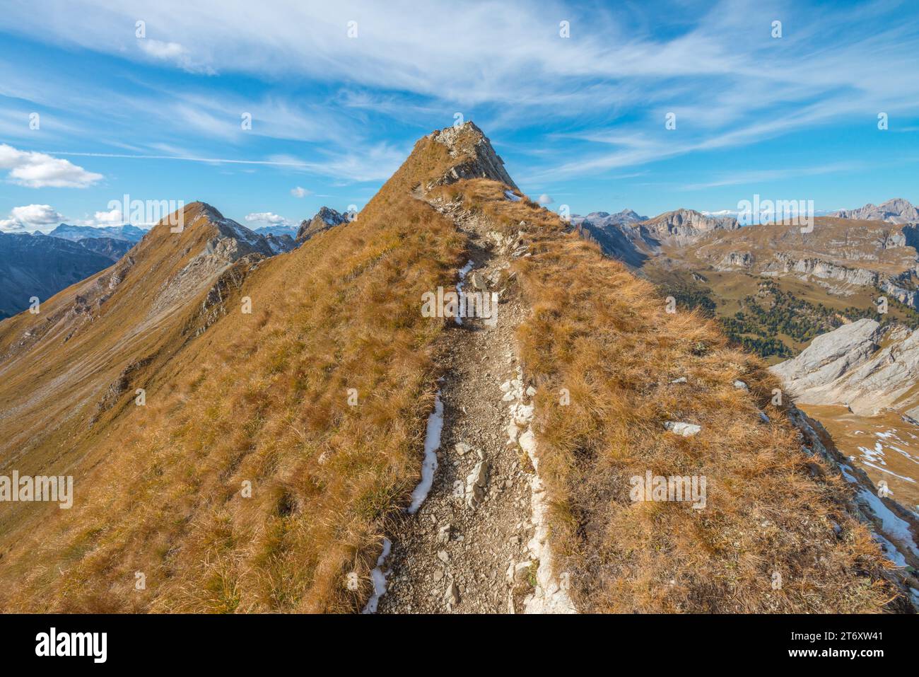Hiker point of view while hiking a ridge trail in the mountains in autumn. Steep ridgeline hiking in the Italian Dolomites. Hiking path. Stock Photo