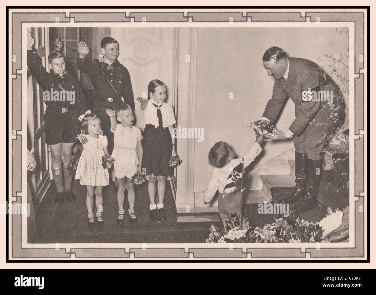 Adolf Hitler with children 1939 Fuhrer of Nazi Germany receiving flowers from an infant, whilst young children with BDM Girl and Hitler Youth in uniform ( Hitler Jugend Hitler Youth) look on giving the Heil Hitler salute. Stock Photo