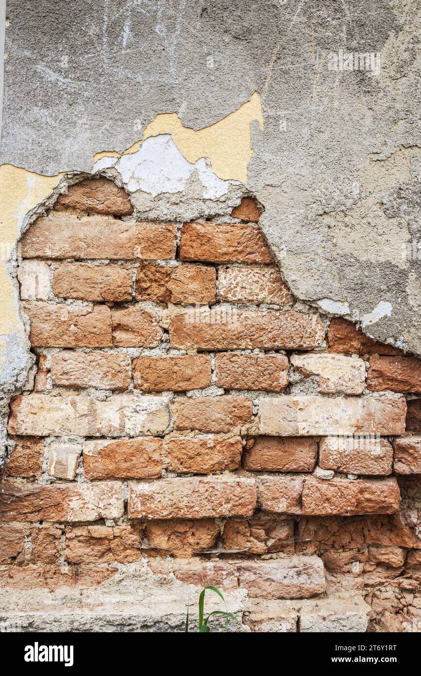 Brick wall with crumbling plaster on old building. Stock Photo