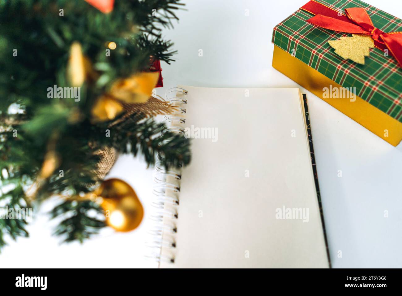 open notepad with blank sheet for wish list text. decorated christmas tree on background Stock Photo
