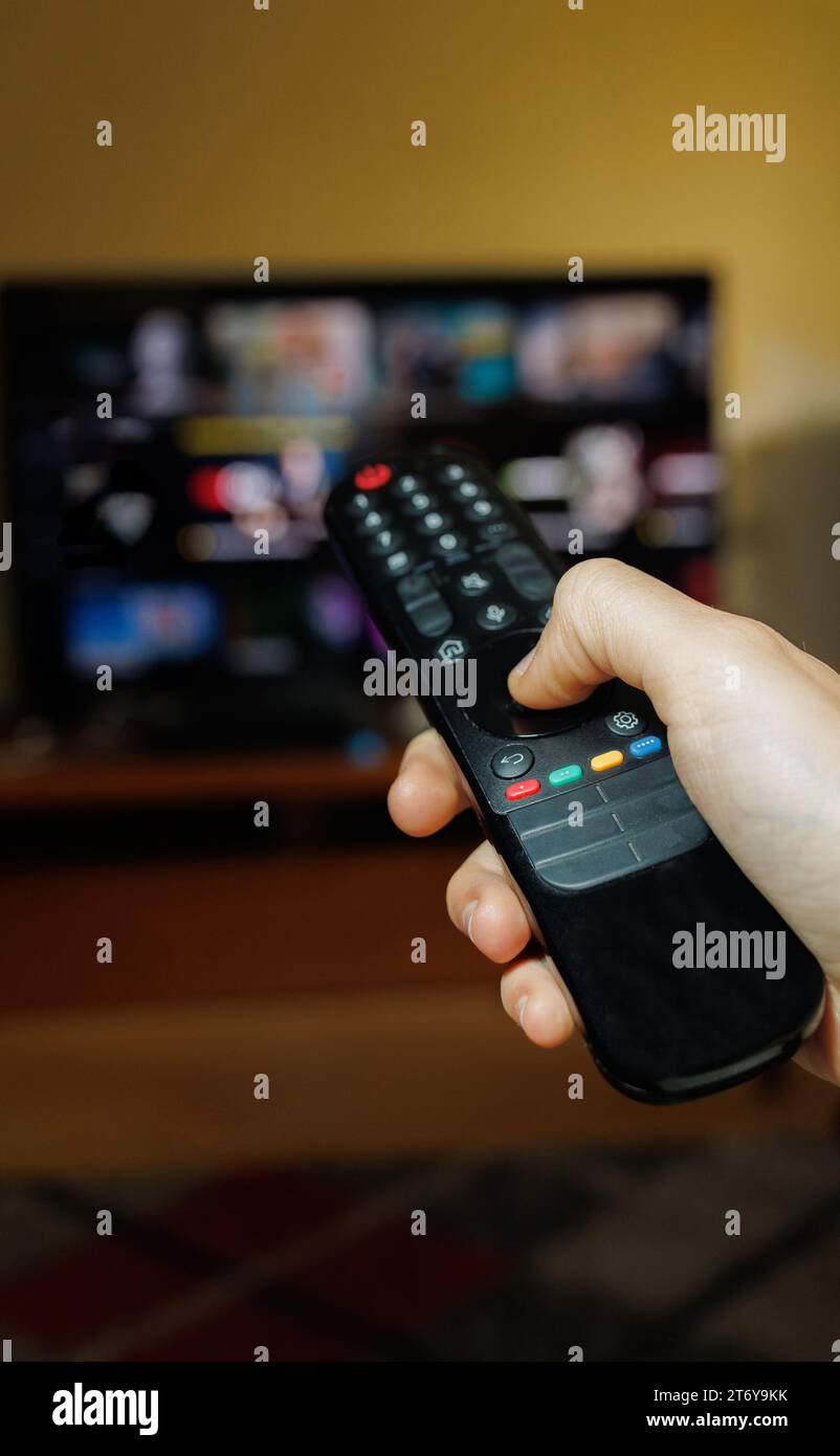 hand holding a TV remote control to change channels and different