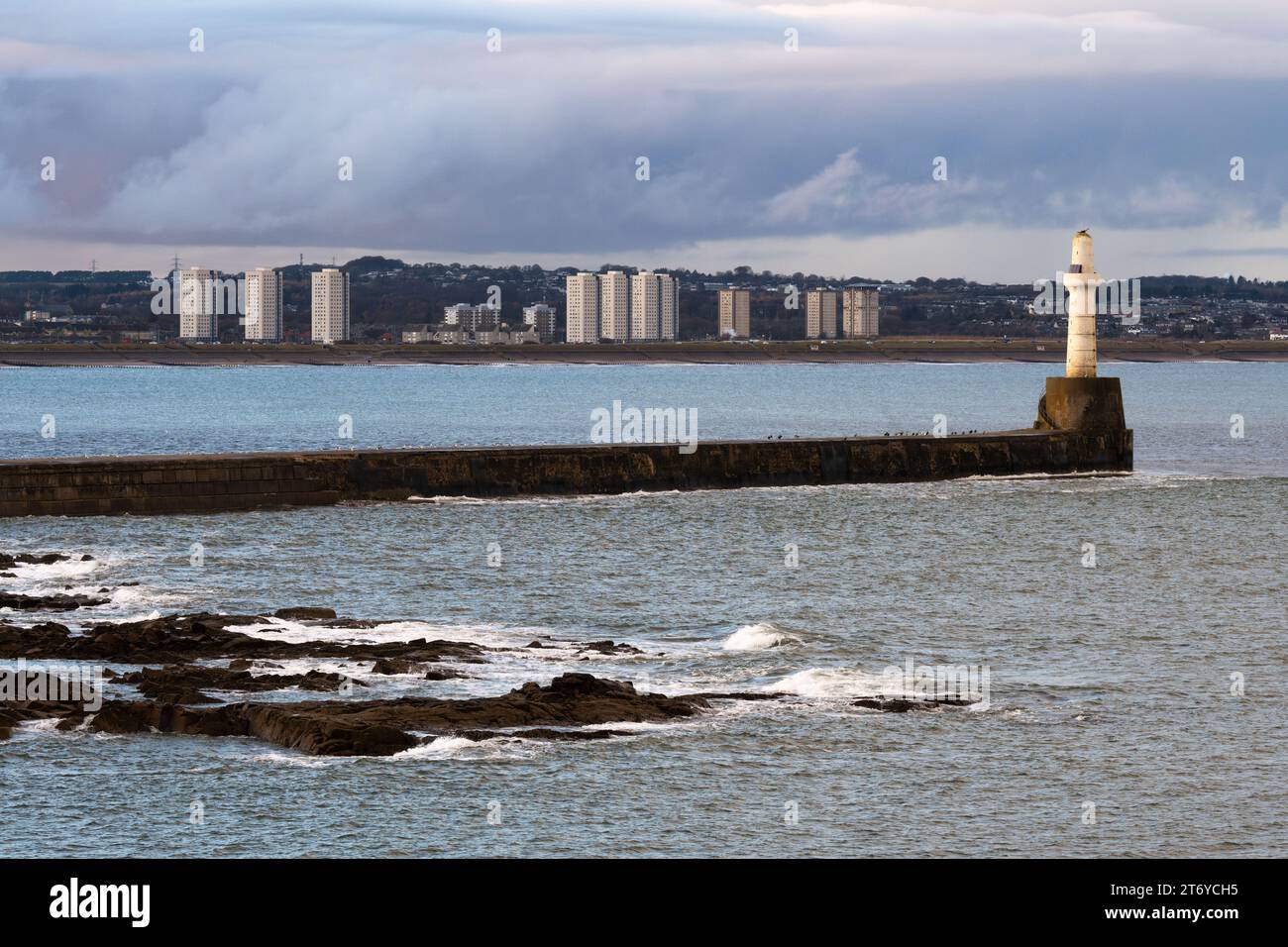 Aberdeen South Breakwater and lighthouse at the entrance to Aberdeen harbour, with the tower blocks at Seaton behind - Aberdeen, Scotland, UK Stock Photo