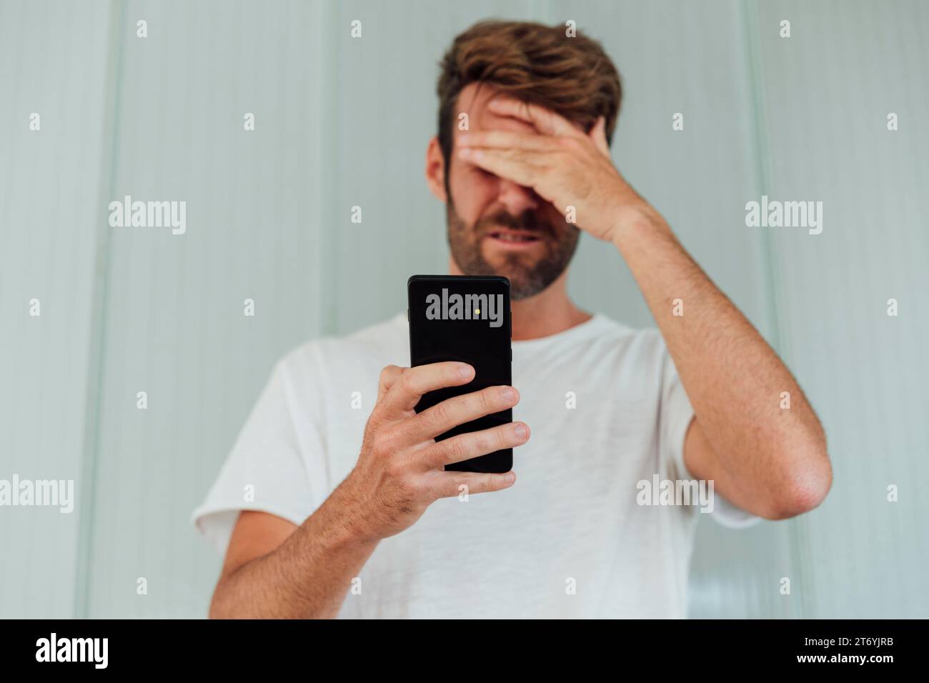 Confused man holding modern phone Stock Photo