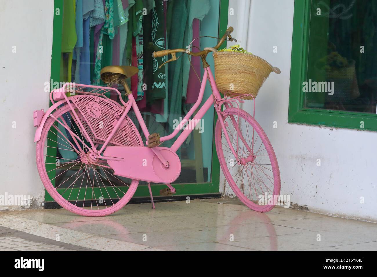 a fully painted pink ladies bicycle with a front basket displayed