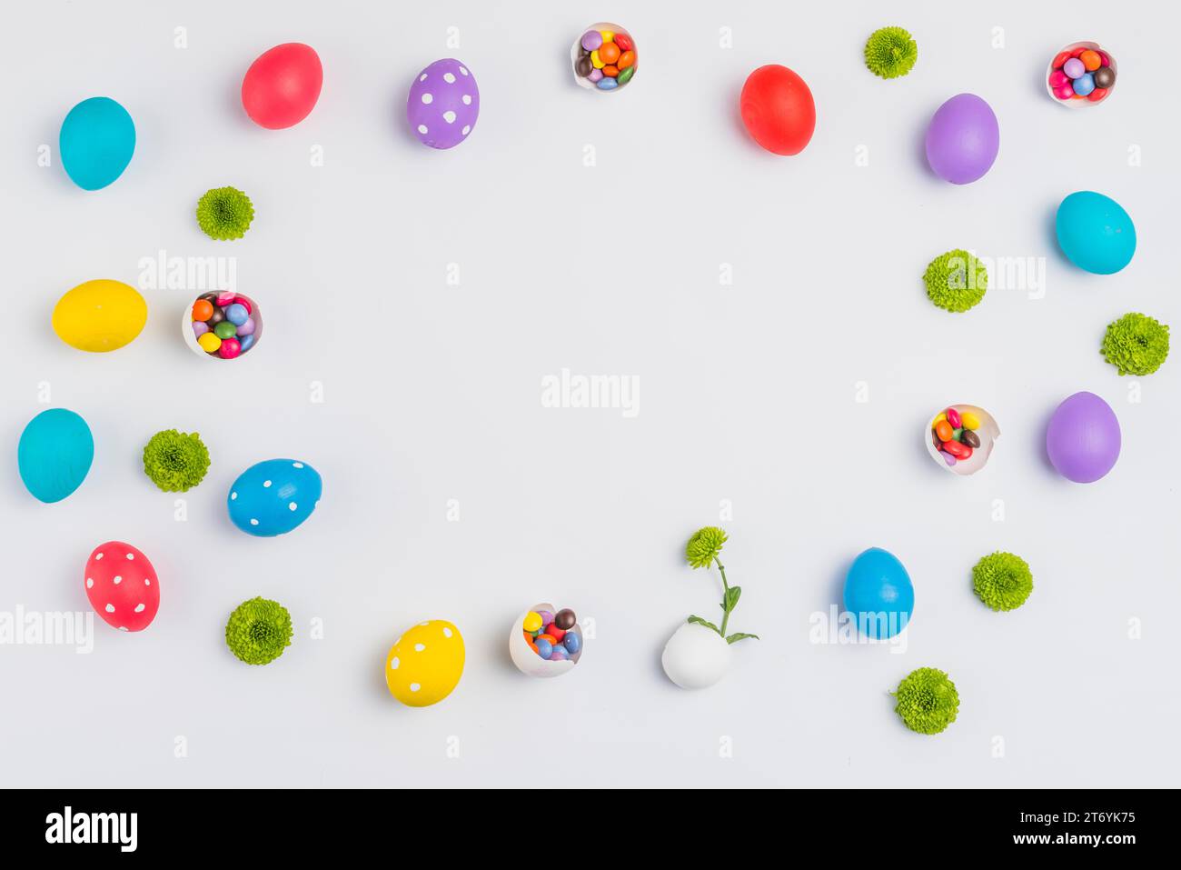 Easter eggs with candies flowers scattered white table Stock Photo
