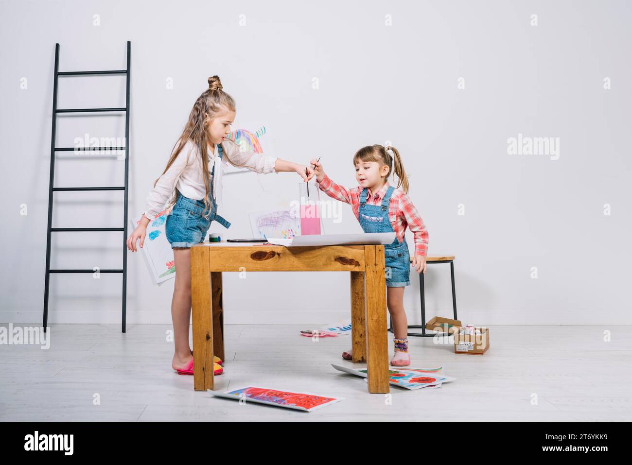 Girls putting paint brushes into water glass Stock Photo Alamy