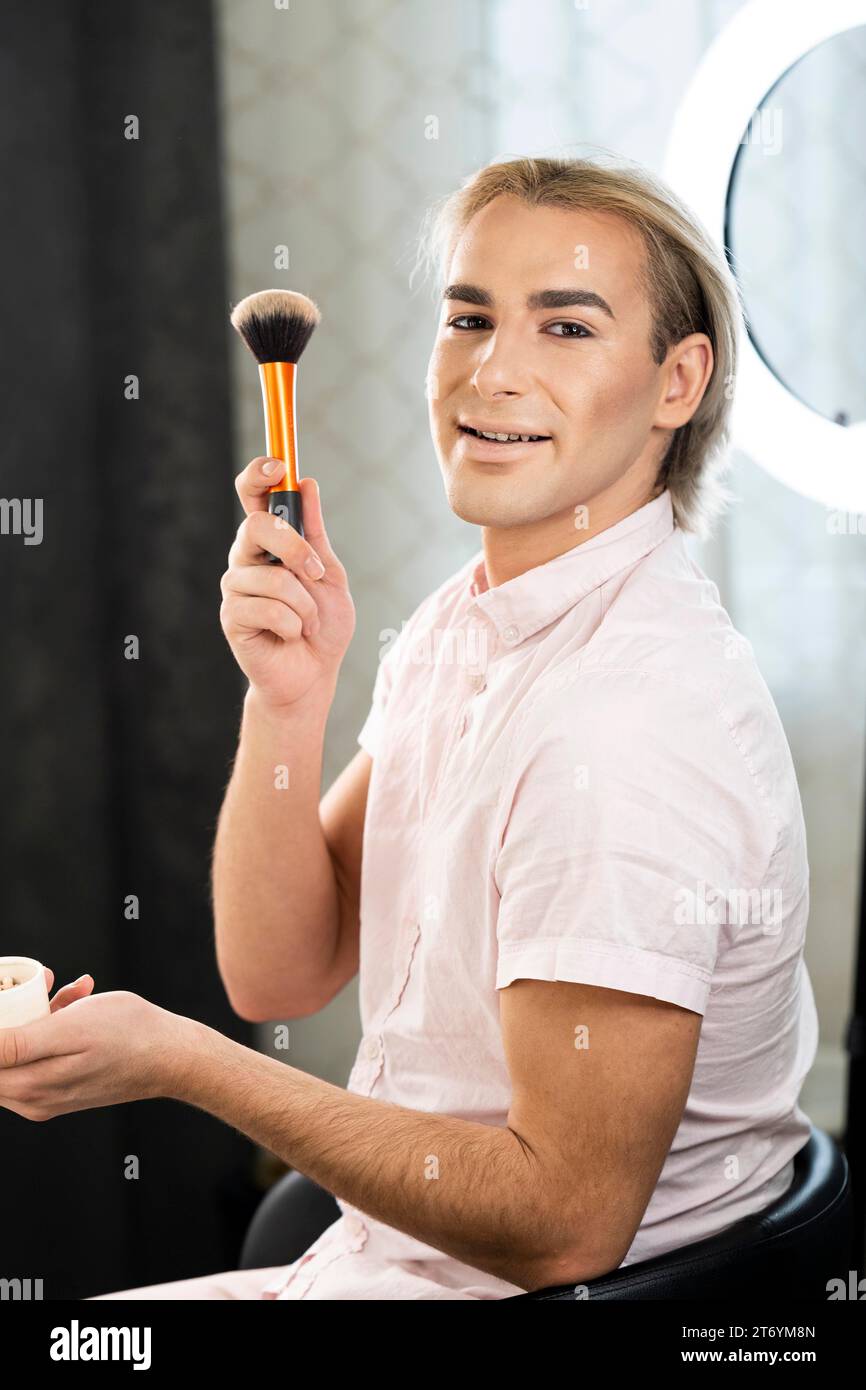 Man wearing make up holding brush side view Stock Photo