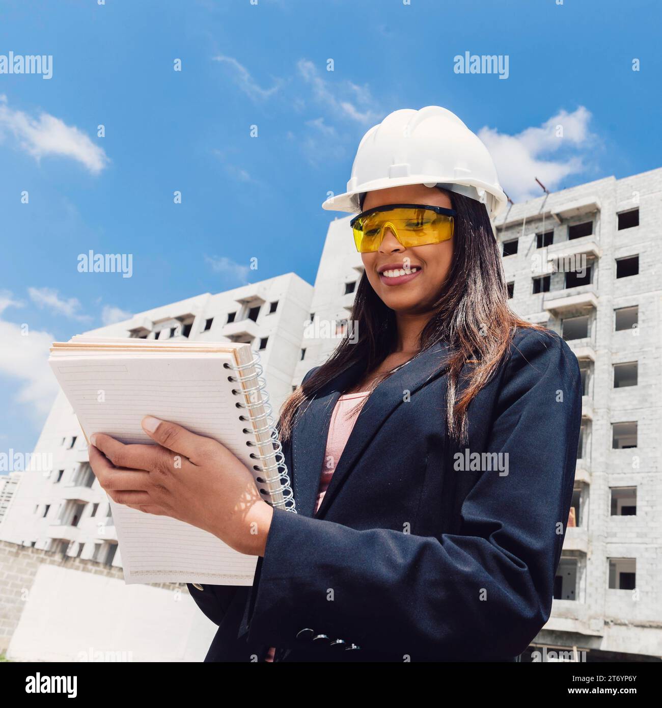 African american lady safety helmet with notebook near building construction Stock Photo