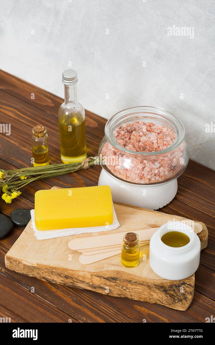 Overhead view himalayan salt jar herbal soap lastone essential oil honey (limonium) flowers table Stock Photo