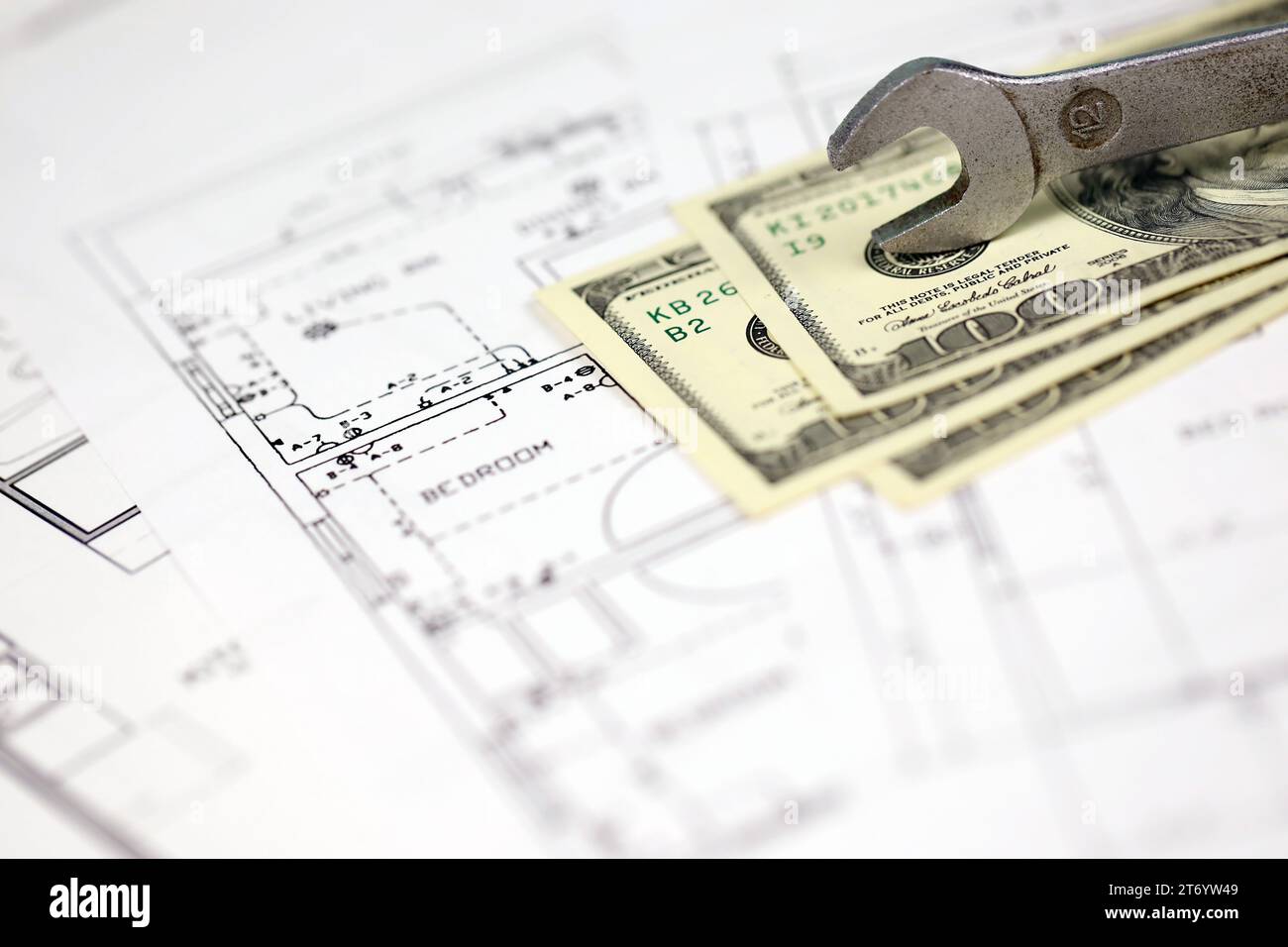 Spanner on top of money with blueprints of residential house plan