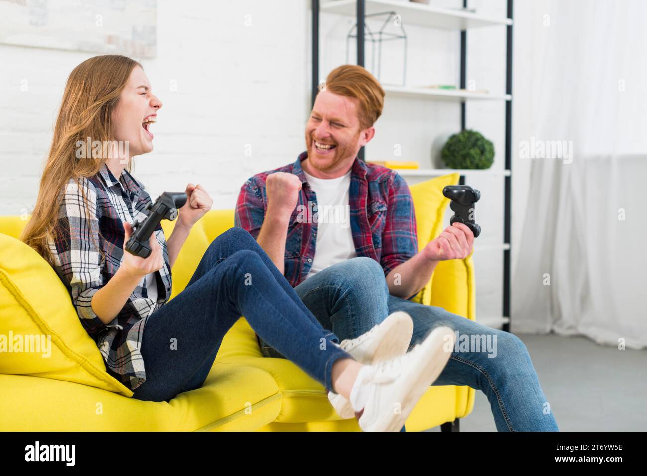 Portrait excited young couple enjoying playing video game home Stock Photo