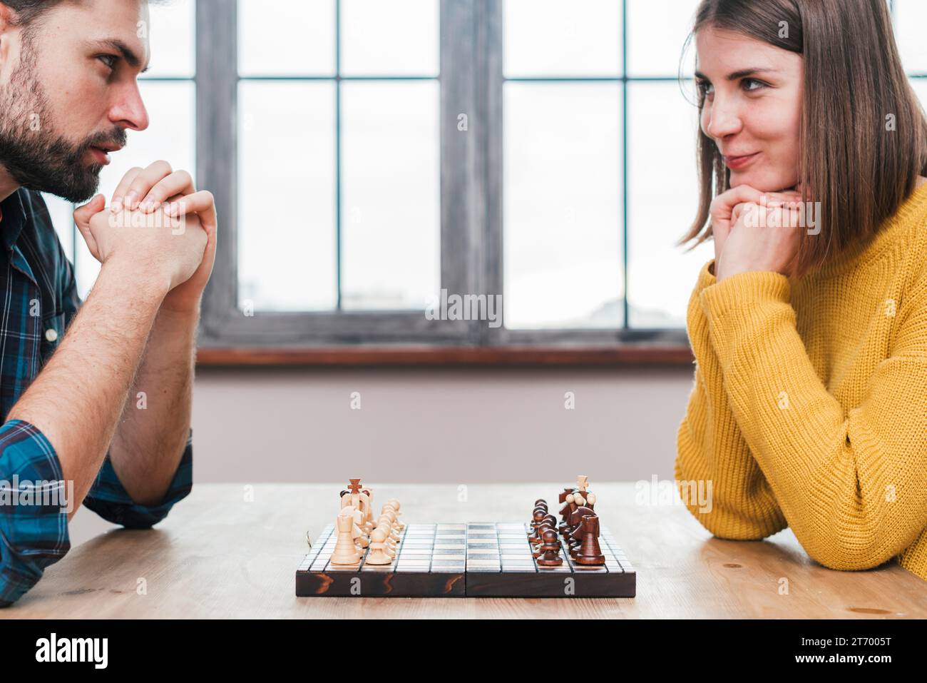Close up young couple with their hand clasped looking each other playing chess Stock Photo