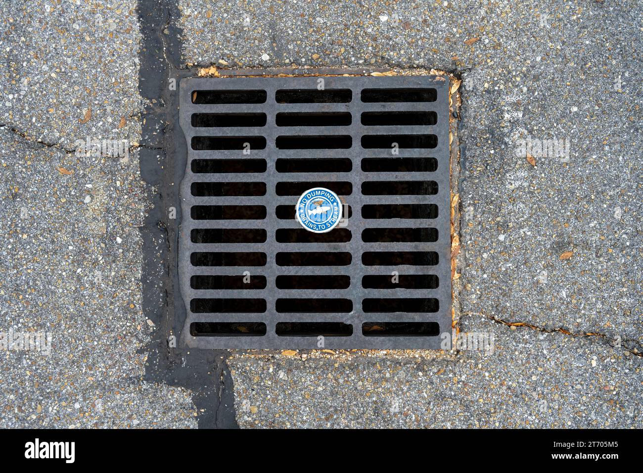 Storm drain in a parking lot with a fish symbol that indicates the drain goes into a nearby stream in an effort to be environmentally safe. Stock Photo
