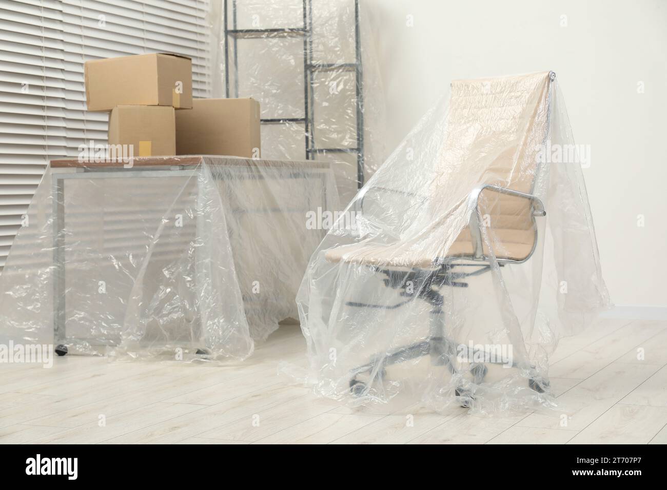 Modern furniture covered with plastic film and boxes at home Stock Photo