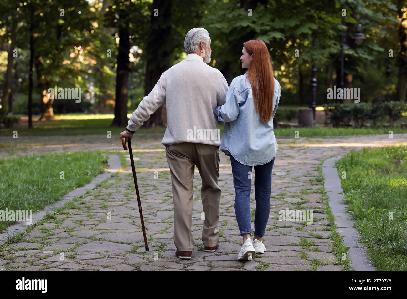Senior man with walking cane and young woman in park, back view Stock ...