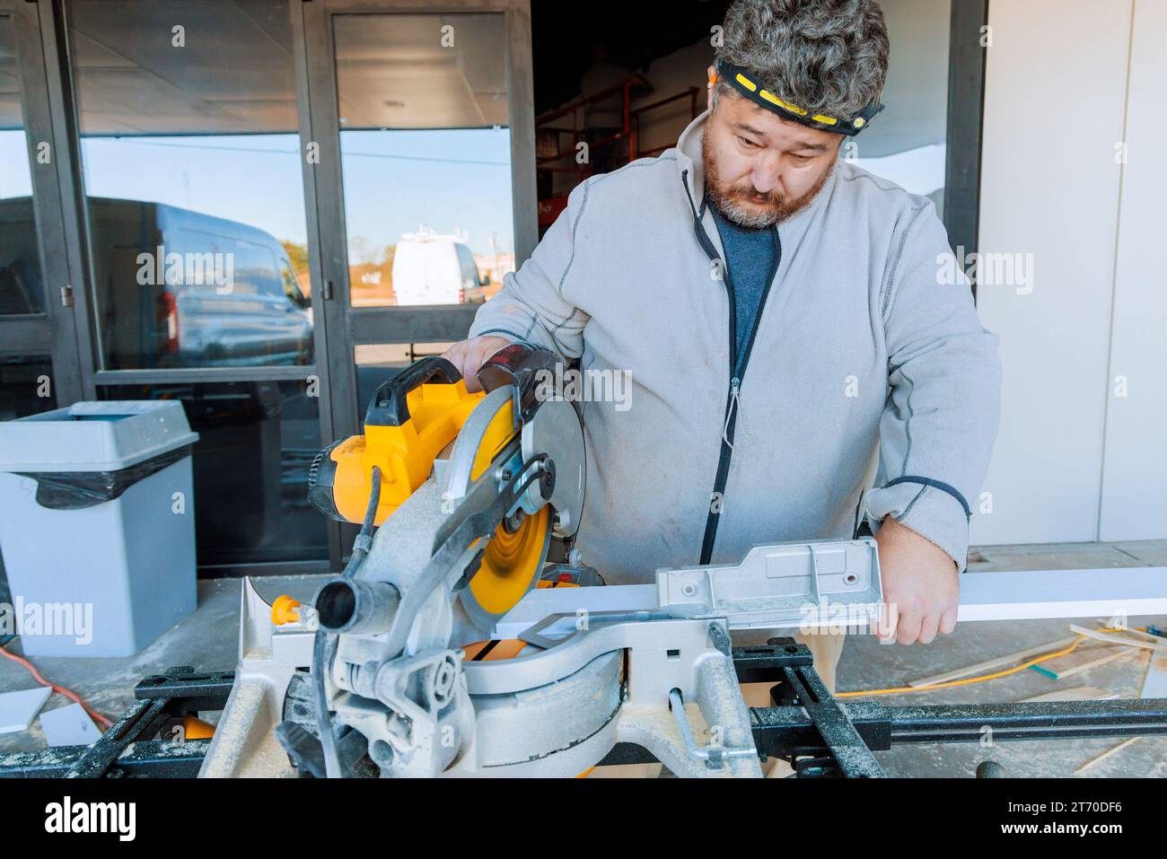 Trim worker cutting base wooden moldings on chop saw tool Stock Photo
