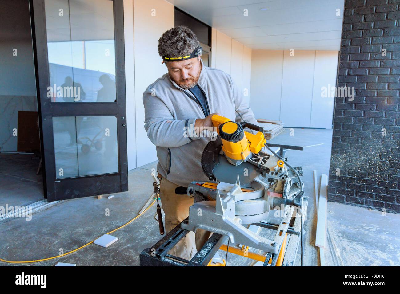 Using chop saw to cut wooden moldings for base of house Stock Photo Alamy