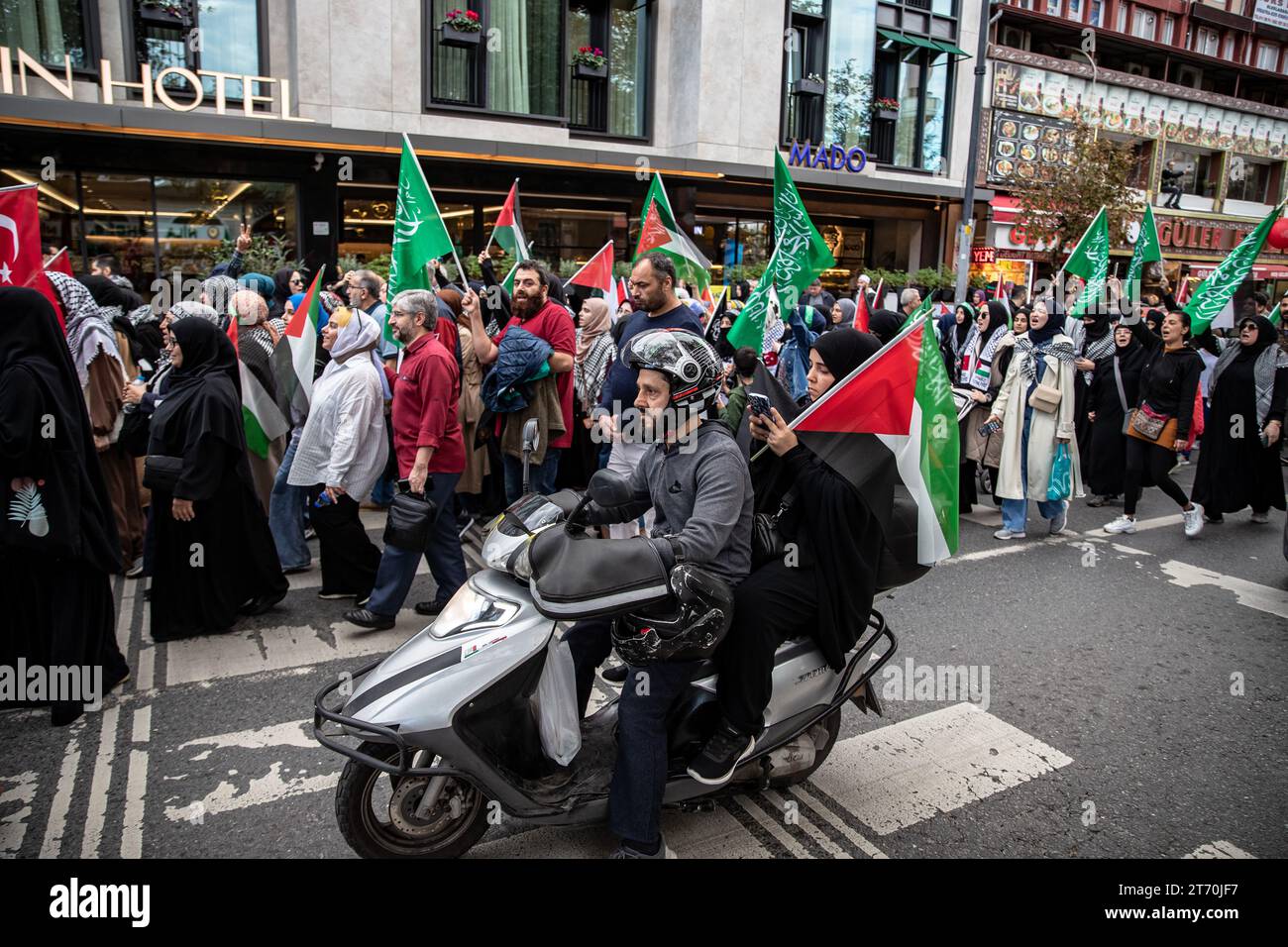 Istanbul, Turkey. 12th Nov, 2023. The passenger behind the motorcyclist passing by the demonstrators walking towards Sultanahmet with Palestinian flags also supported them with the Palestinian flag. Palestine Initiative Platform formed a human chain from Edirnekapi to Sultanahmet to protest Israel's attacks on Gaza. Credit: SOPA Images Limited/Alamy Live News Stock Photo